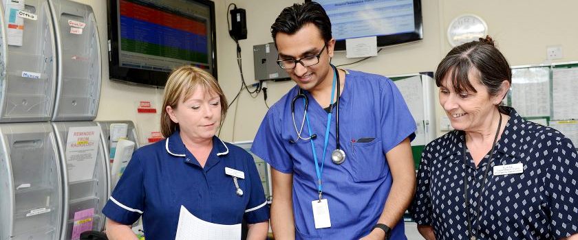 A mix of clinical and non clinical staff reading through paperwork.