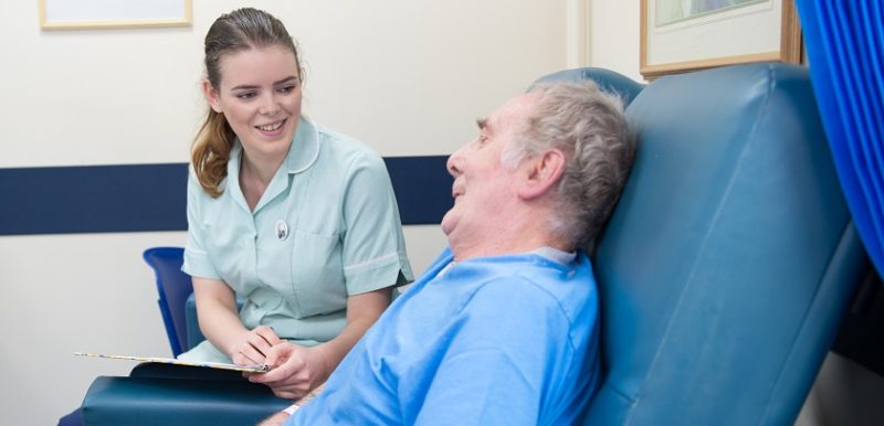 Female nurse sat with male patient, they are both smiling