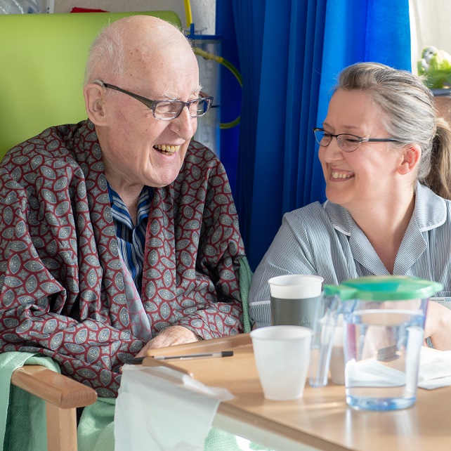 Female nurse laughing with male patient