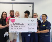 Heather, Luke and Ella Butler with staff from the Neonatal Unit holding a giant cheque.