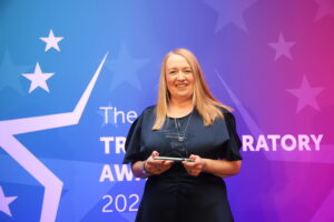 Photograph of staff member Janice Llewellyn holding her award at The Trust Celebratory Awards 2024