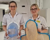 Two female Radiographers holding the new and old style of masks used for Radiotherapy.