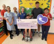 Bryce Corden presents a cheque to a patient and staff on the children's ward