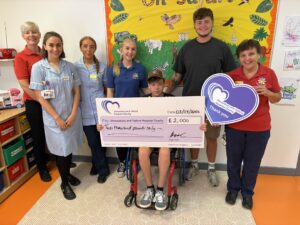 Bryce Corden presents a cheque to a patient and staff on the children's ward